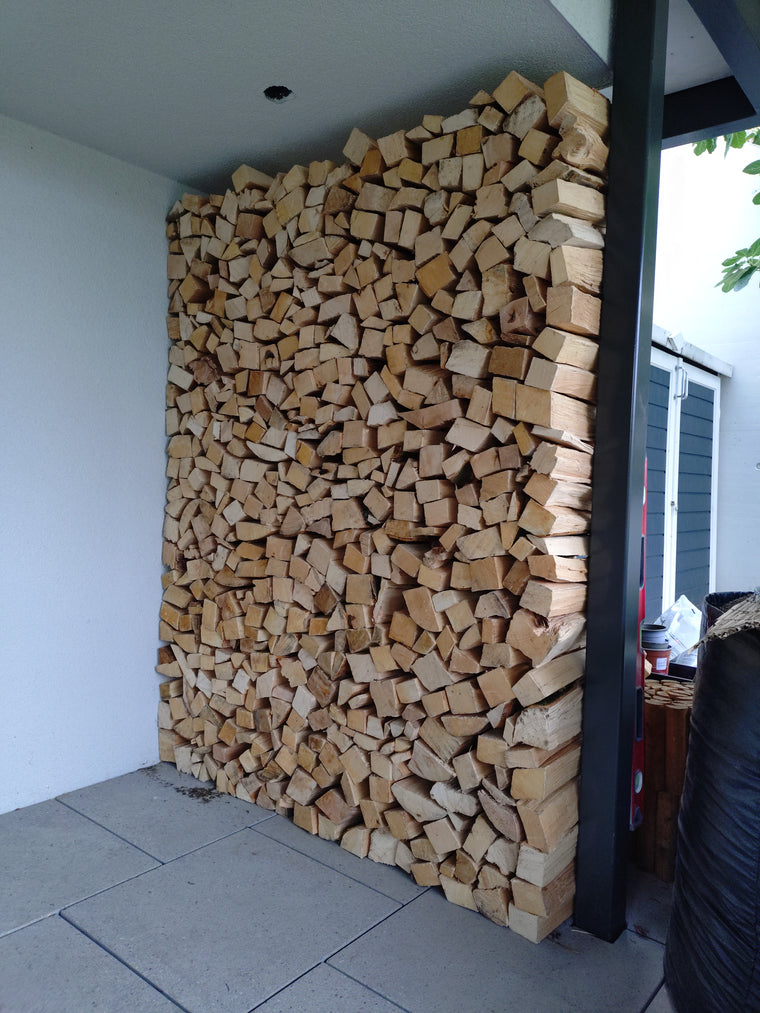 Aufgeschichtetes Buchenholz vor einem Haus
